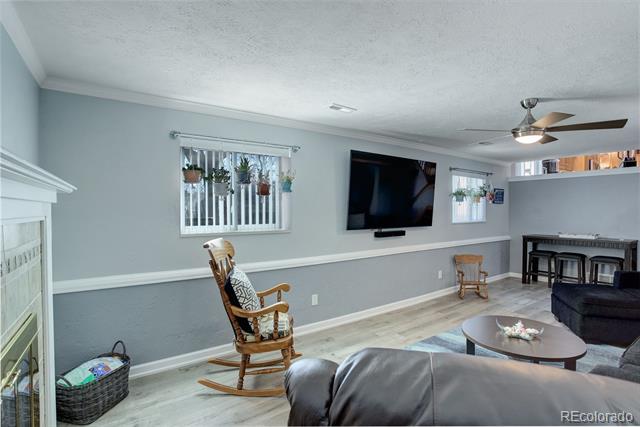 Living room with a wall-mounted television, rocking chair, and gray sofa.