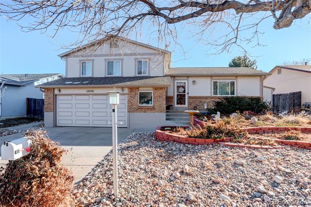 Two-story home with brick facade, attached garage, and rock landscaping in front.
