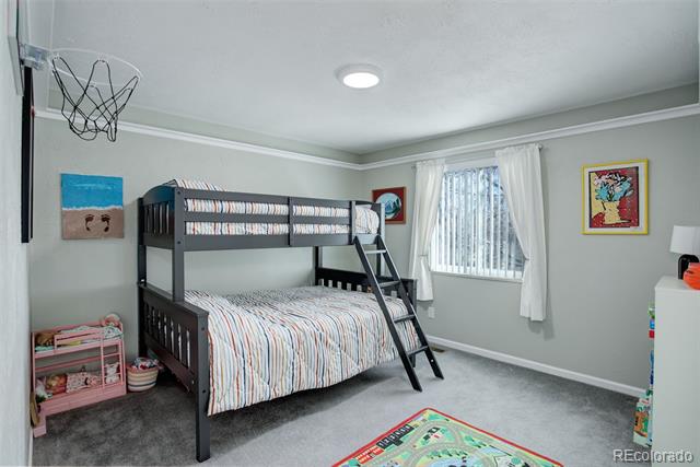 Bedroom with a dark wood bunk bed, striped bedding, and a small basketball hoop.