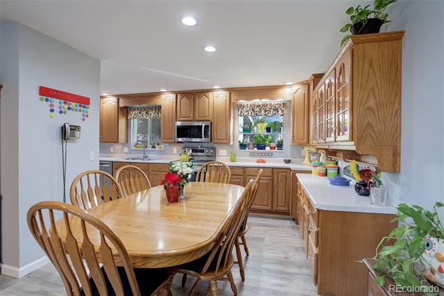 Kitchen with honey-colored cabinets, two windows, and a round wooden dining table.