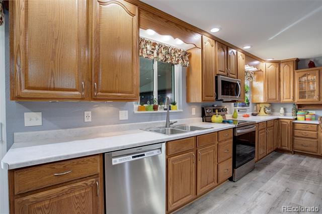 Kitchen with honey-colored wood cabinets, white countertops, and stainless-steel appliances.