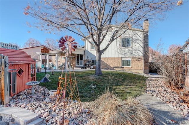 Rear of a two-story house with a patio, red shed, and metal windmill ornament.