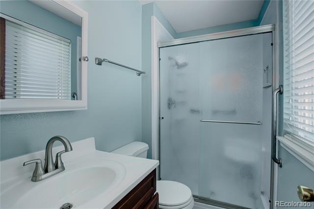 Bathroom with a white vanity, toilet, and frosted-glass shower enclosure.