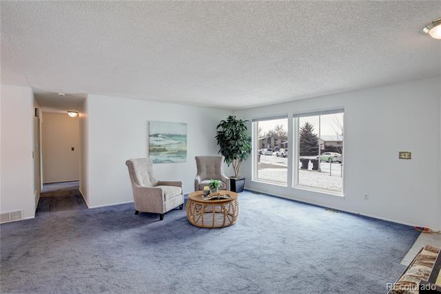 Living room with two chairs and wicker coffee table beside large windows overlooking a snow-dusted street.