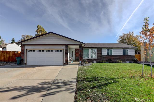 Single-story brick house with a two-car garage, wide driveway, and green front lawn.