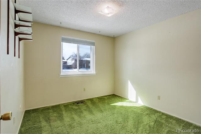 Empty carpeted room with a window overlooking a snowy yard and short wall-mounted shelves.