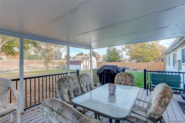 Covered patio with outdoor dining set and barbecue overlooking a fenced backyard.