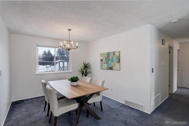 Dining room with a wood table, upholstered chairs, chandelier, and snowy view through the window.