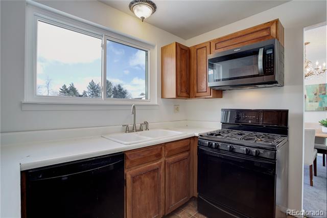 Kitchen with wood cabinets, white countertops, and a sink beneath a wide window.