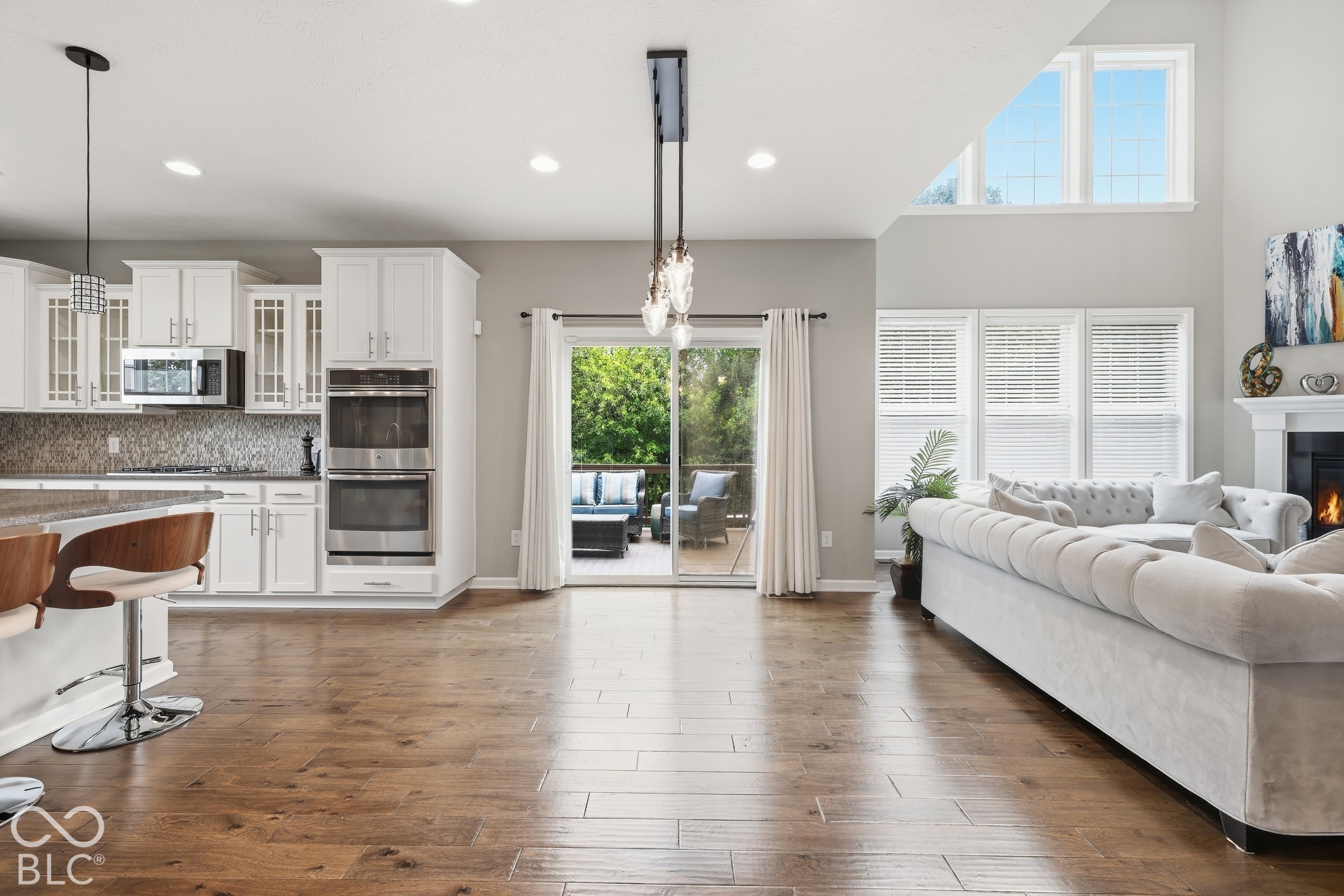 Open-plan kitchen and living room with white cabinetry, a white sectional, and a sliding door to the patio.