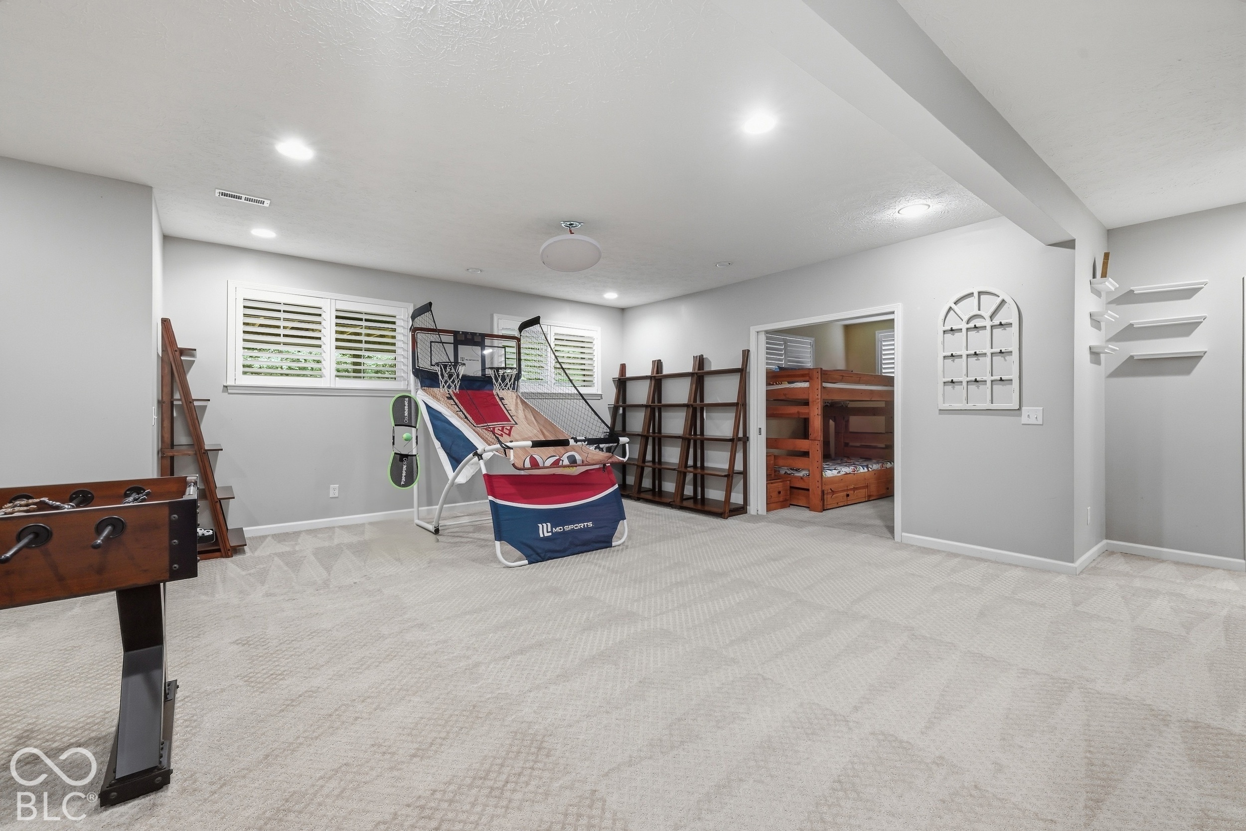 Carpeted recreation room with a foosball table, basketball arcade game, and bunk beds.