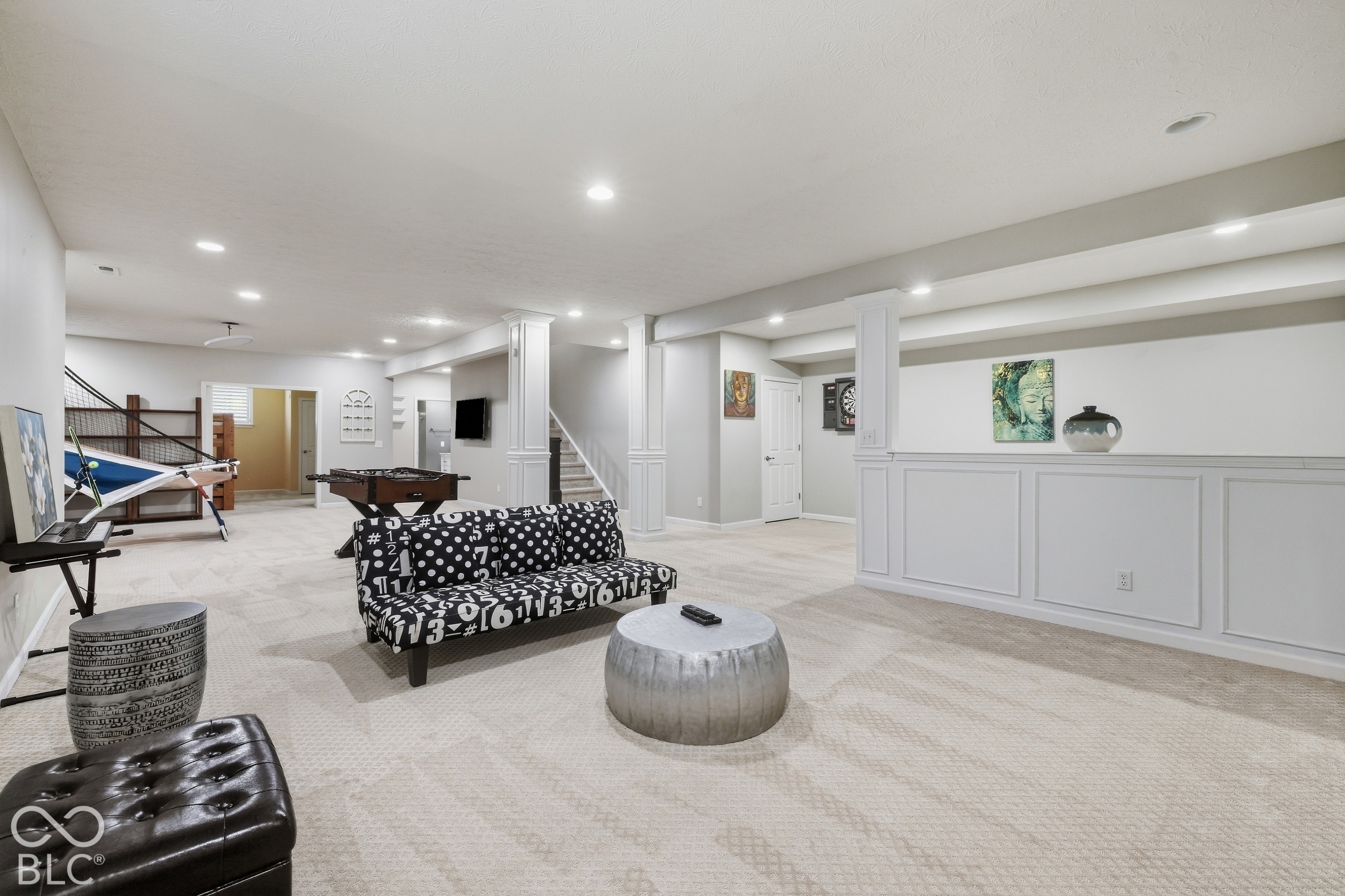 Basement recreation room with a patterned sofa, foosball table, and indoor hammock.