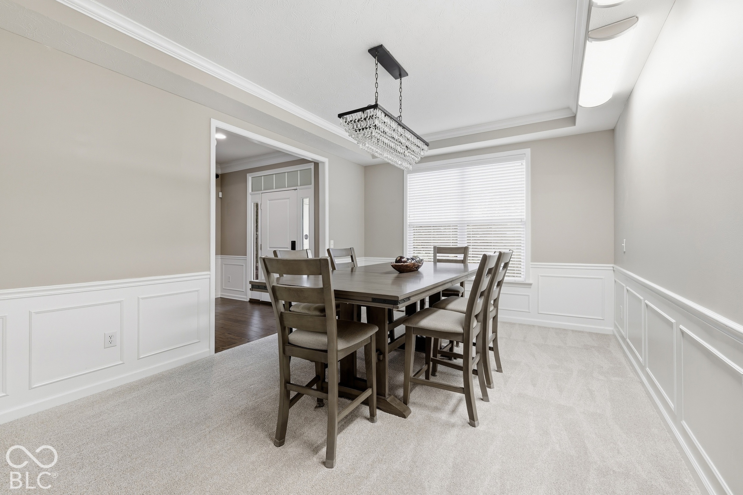 Dining room with a dark wood table, upholstered chairs, and crystal chandelier.