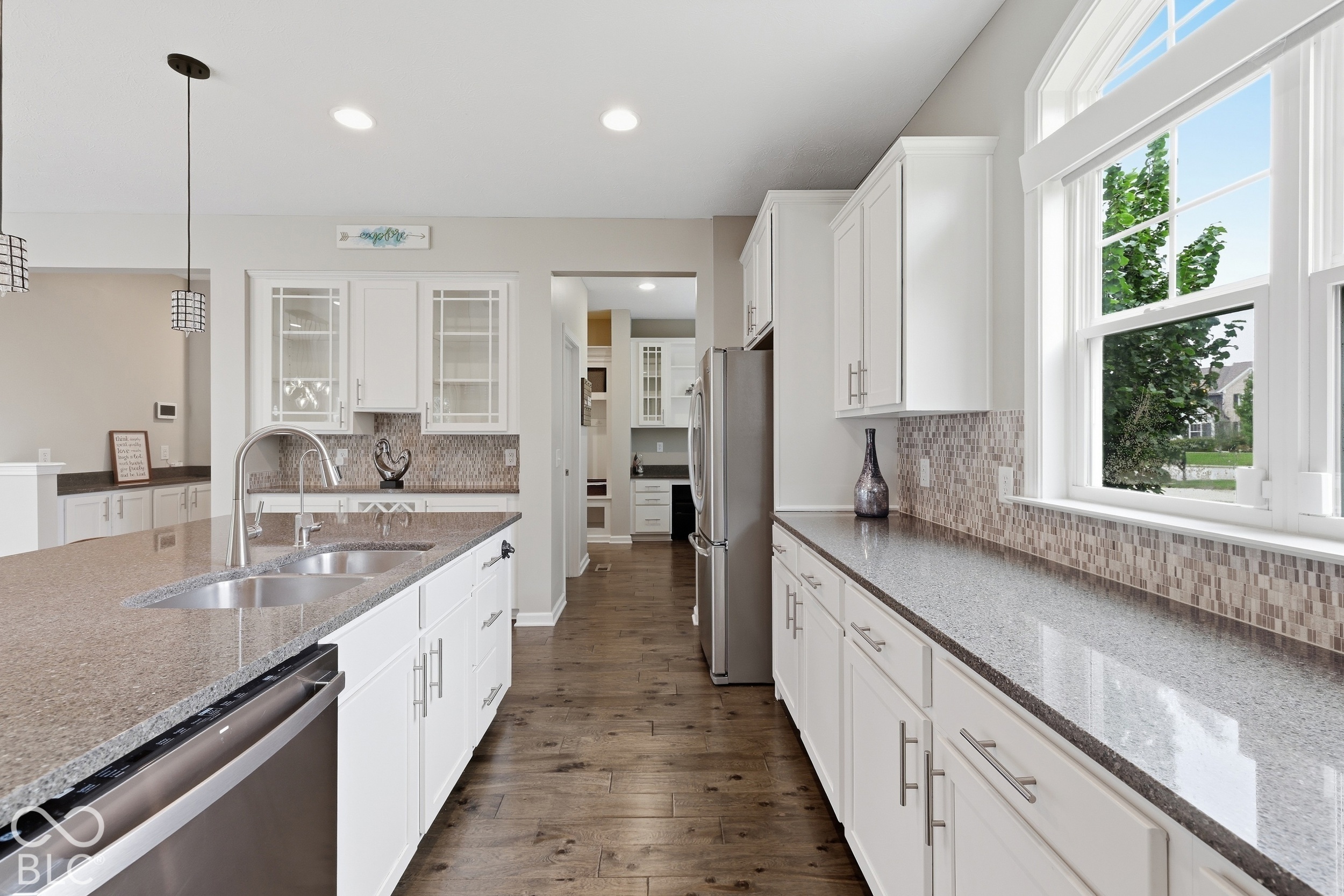 Kitchen with white cabinets, gray stone counters, a large island, stainless appliances, and wide windows.