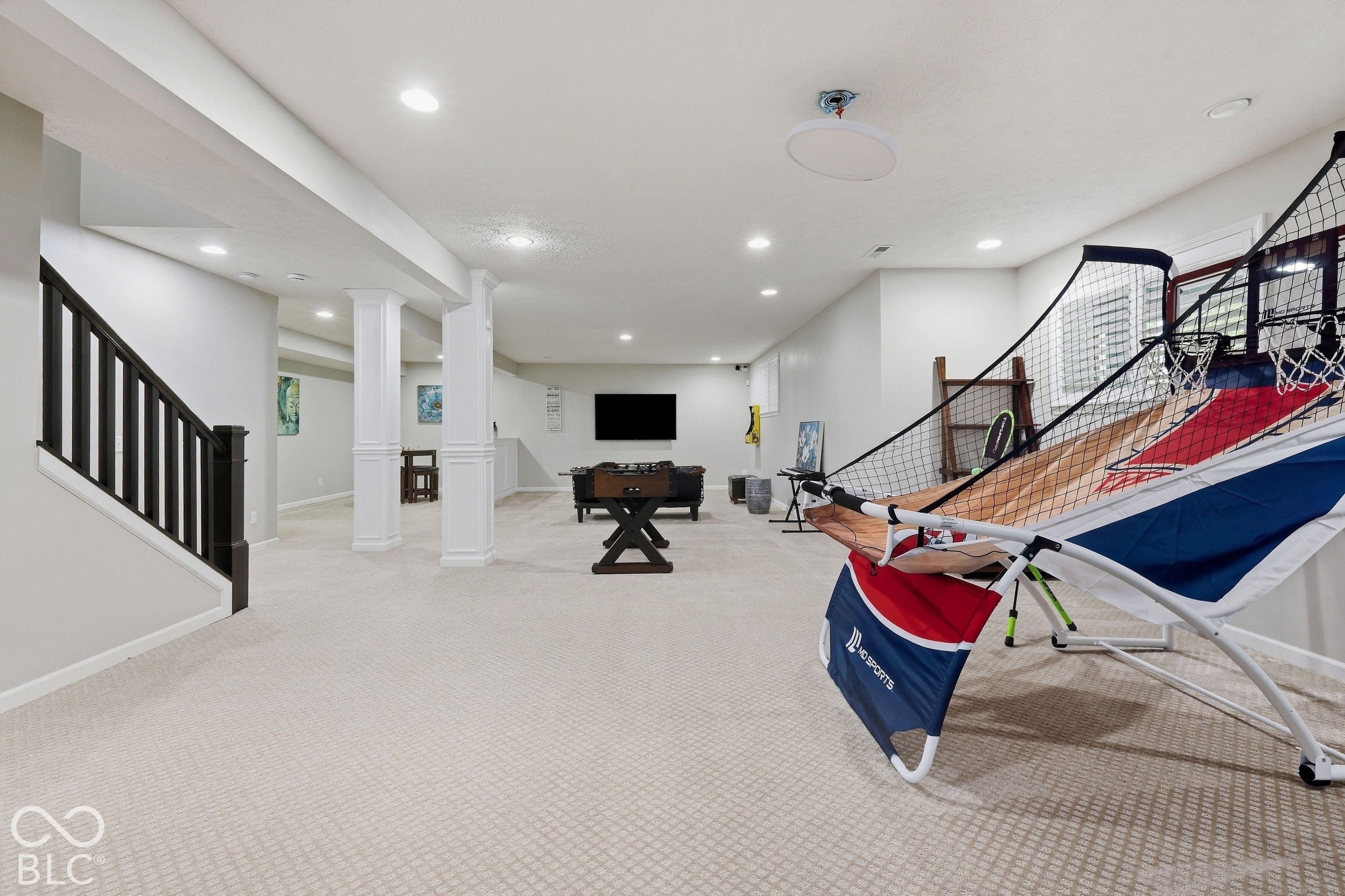 Finished basement recreation room with a foosball table, carpeted floor, and large netted sports equipment.