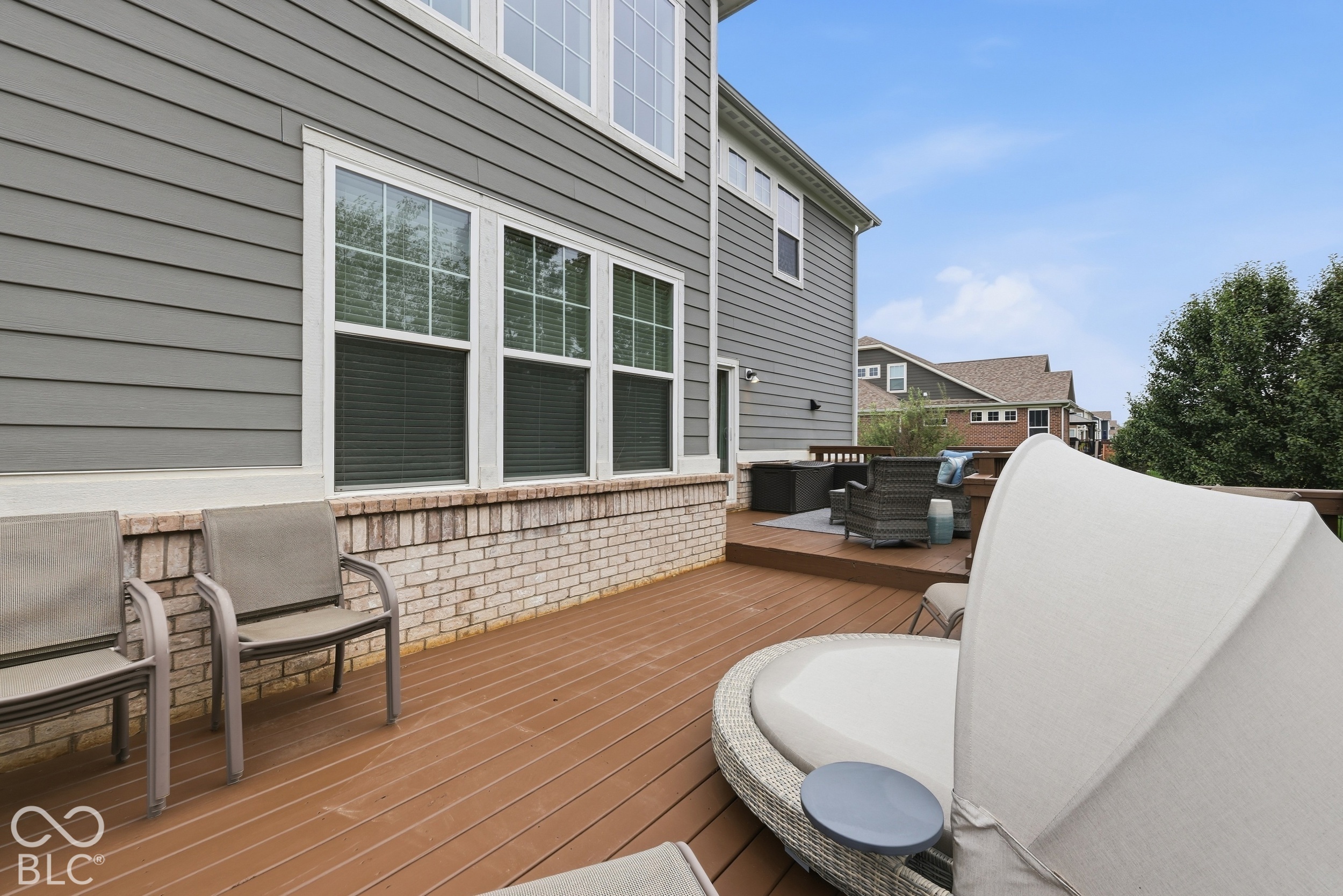 Backyard deck with brown decking, patio chairs, and a raised outdoor seating area.