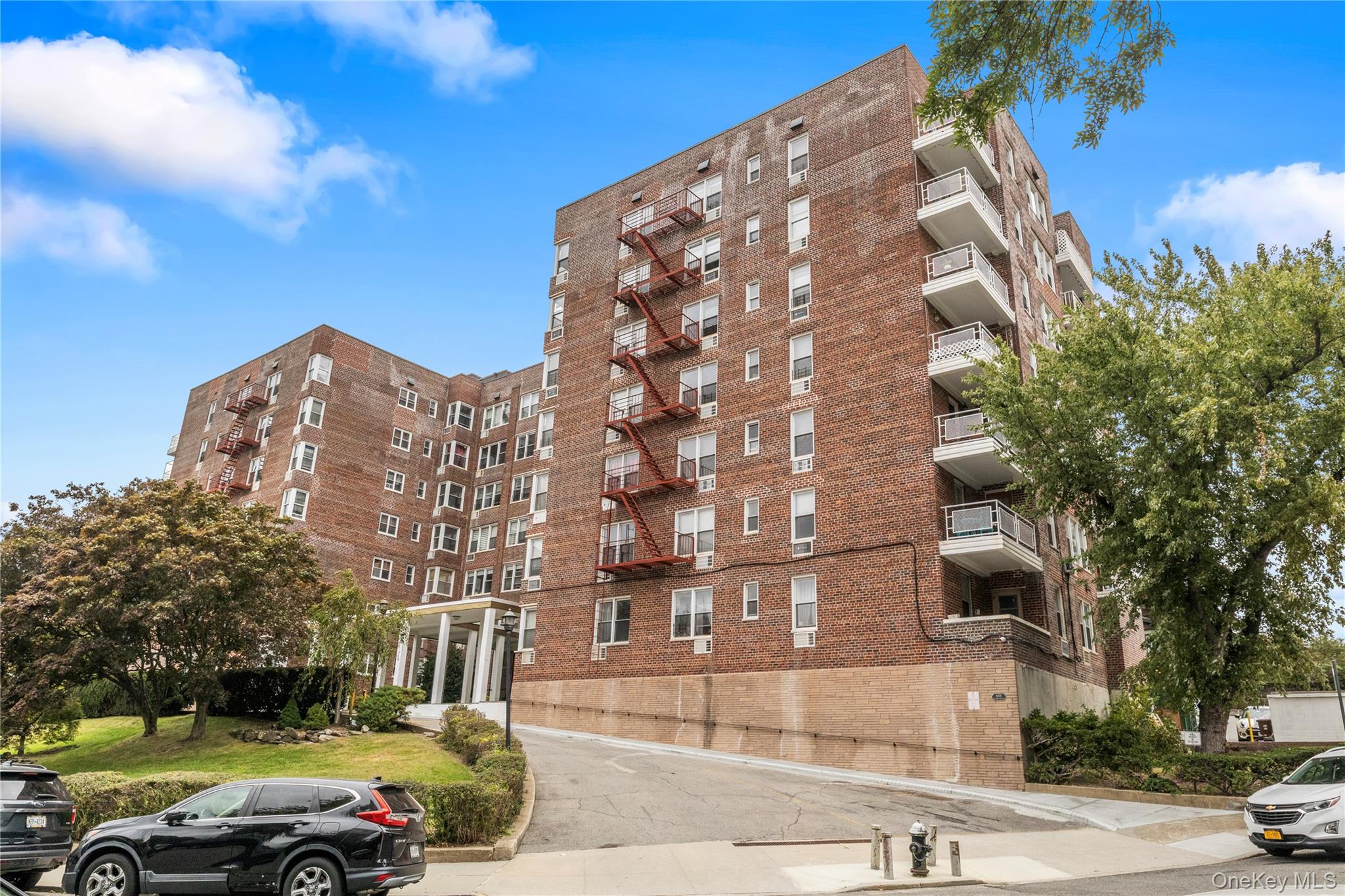 Red-brick apartment building with fire escapes, balconies, and a covered entrance.