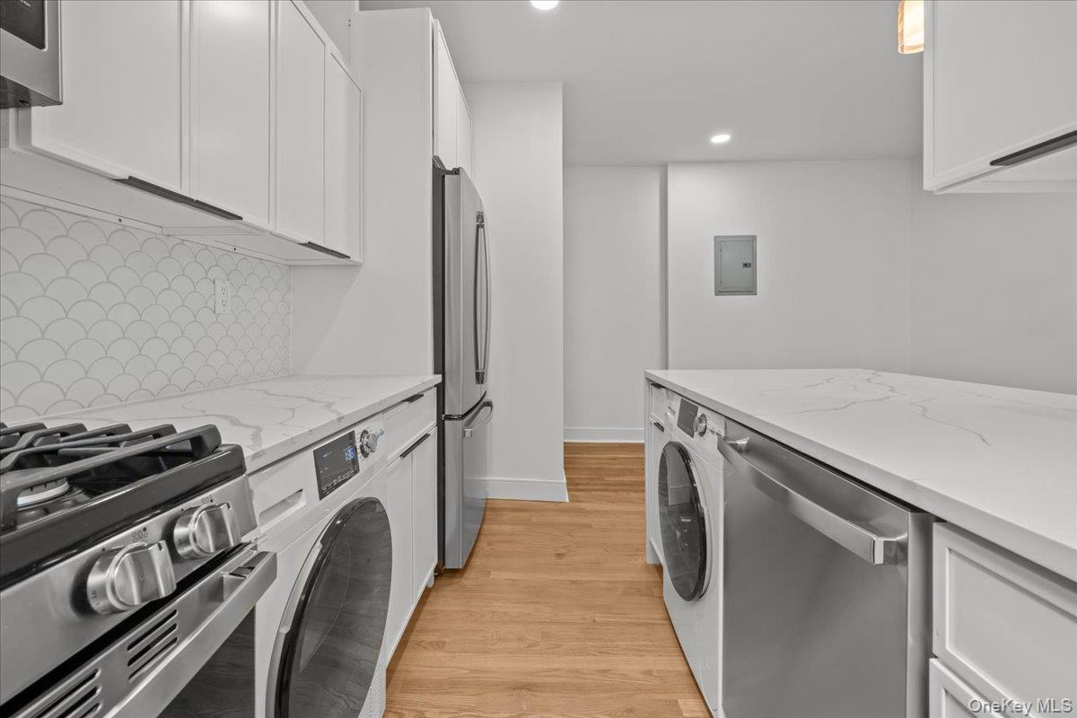 Modern kitchen with scallop-pattern backsplash, veined countertops, and built-in laundry appliances.