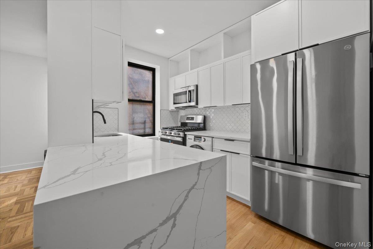 Modern kitchen with a large veined stone island and stainless steel appliances.