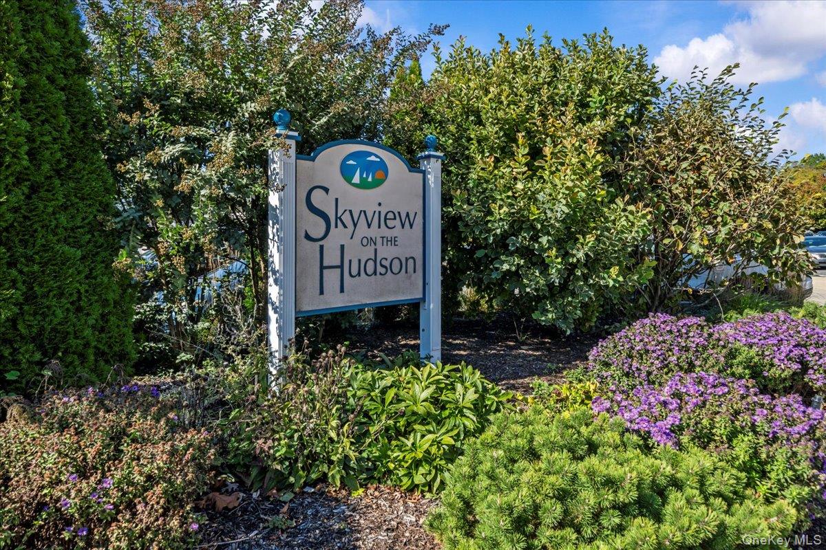 Skyview on the Hudson entrance sign amid shrubs and purple flowers.