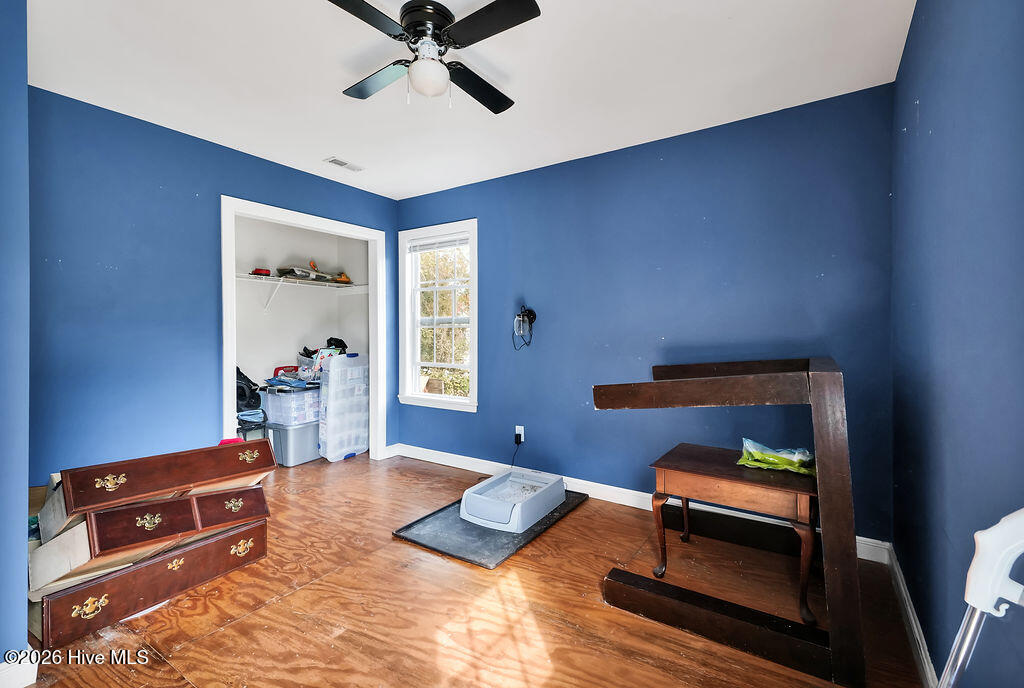 Blue-walled room with hardwood flooring, a closet, and a window.