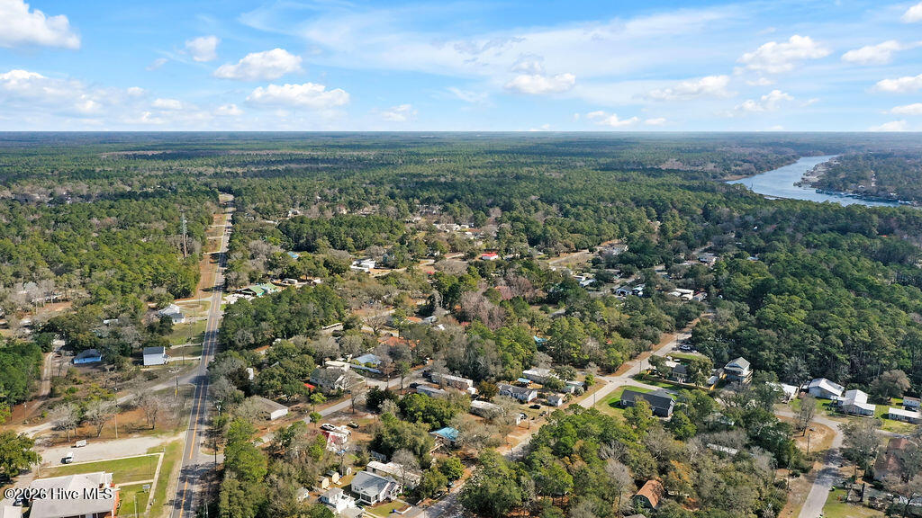 Aerial view of a wooded Bolivia neighborhood, with homes, roads, and a river in the distance.