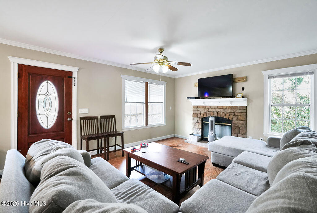 Living room with gray sectional sofas, a stone fireplace, and large windows.