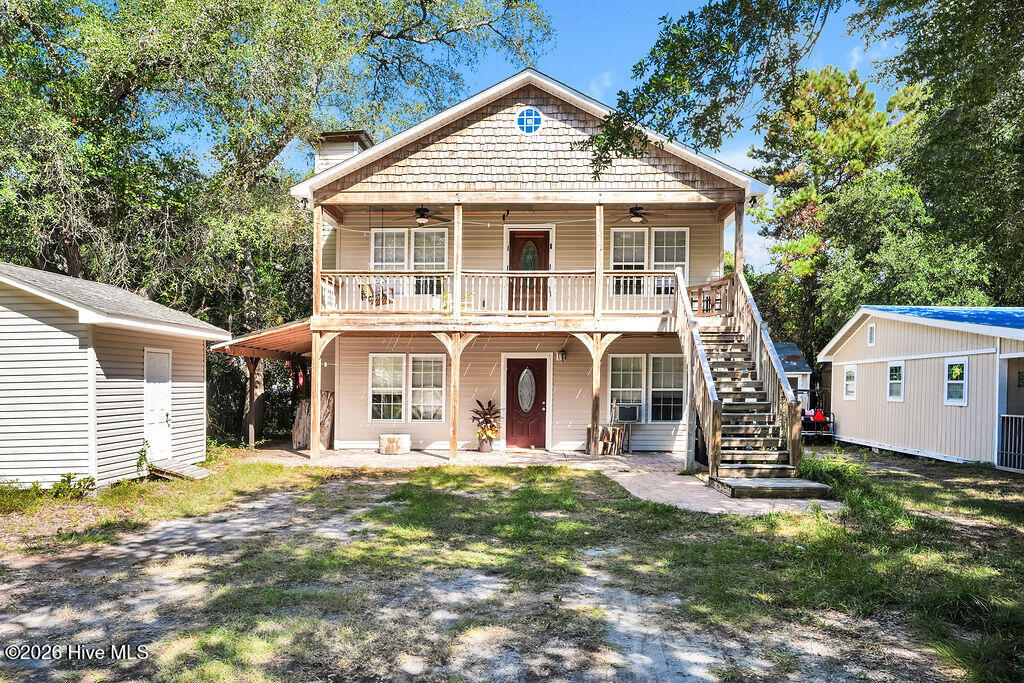 Two-story home with a covered porch, upper balcony, and exterior staircase.