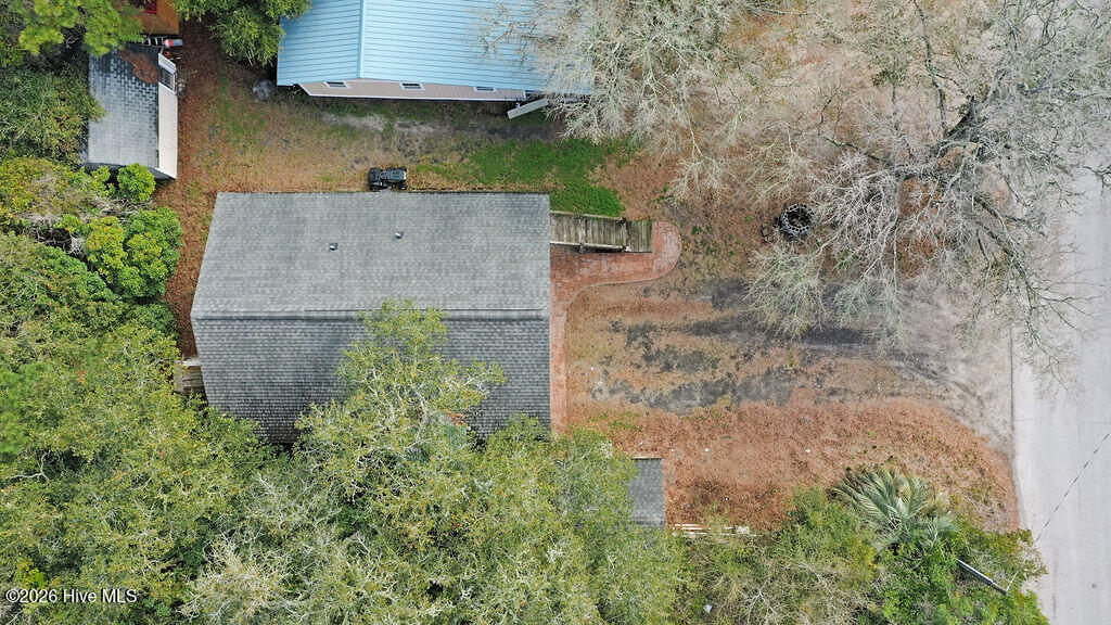 Aerial view of a house with a large gray roof, brick patio, and mature trees.