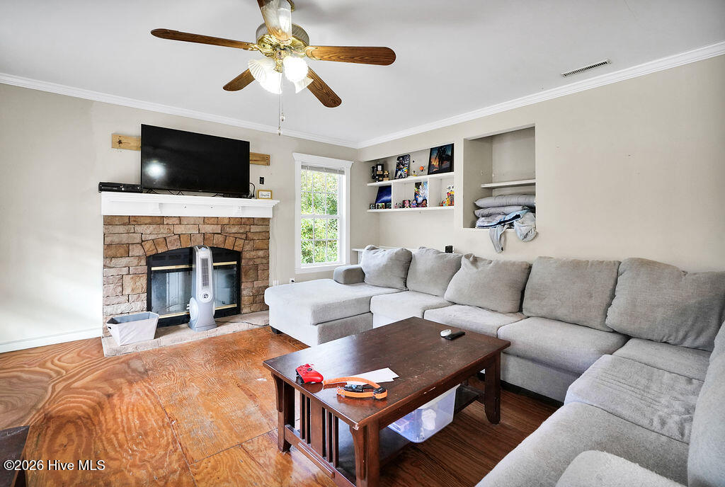 Living room with a gray sectional, stone fireplace, and mounted television.