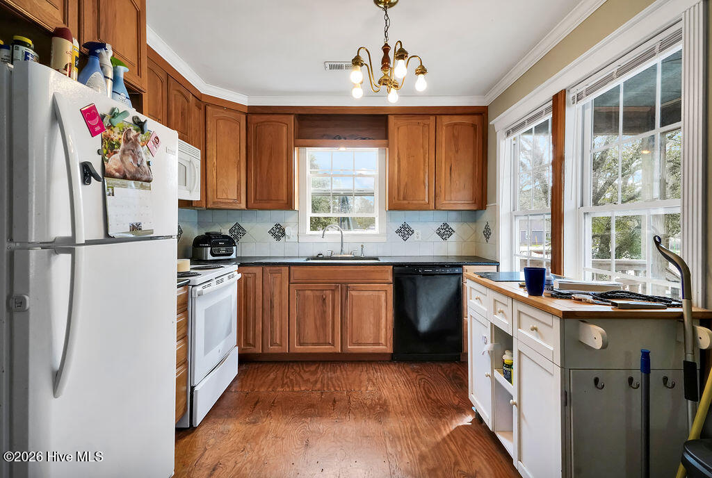 Kitchen with warm wood cabinets, wood flooring, and a counter beside large windows.