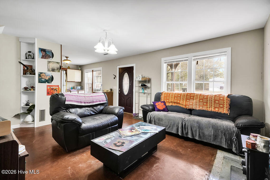 Living room with black leather seating, large windows, and a dark coffee table.