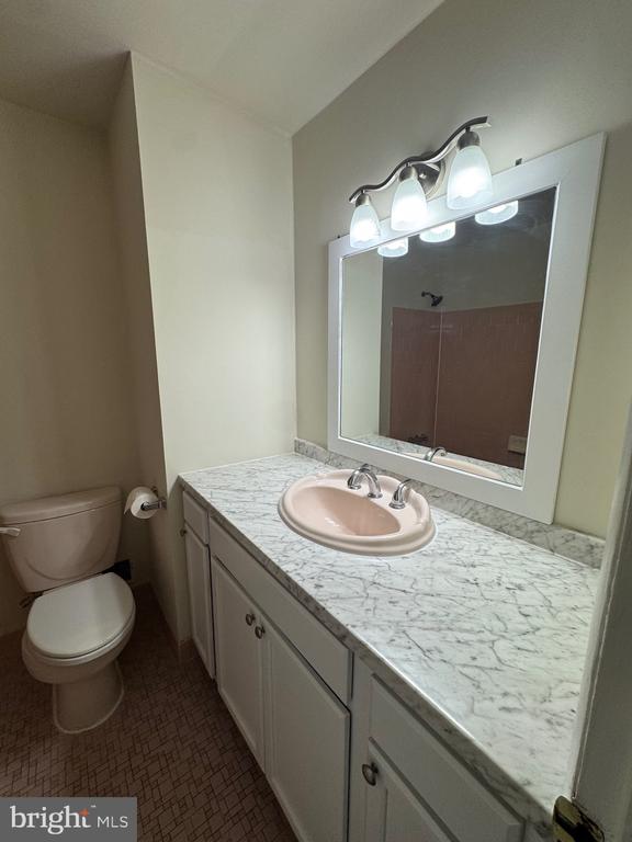Bathroom with a marble-look vanity, pale pink sink, large mirror, and toilet.