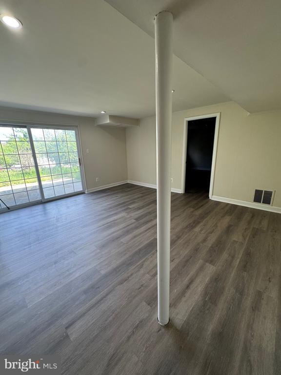 Vacant living room with gray plank flooring, a central support column, and sliding glass doors.