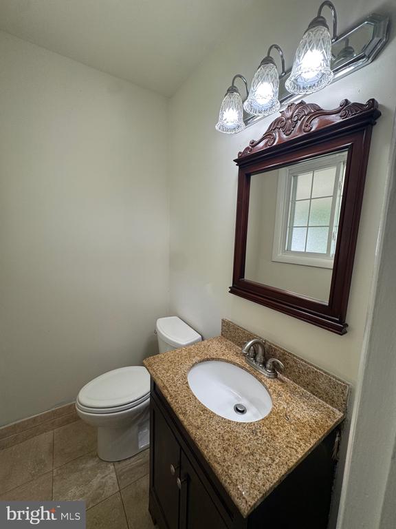 Bathroom vanity with a speckled granite counter, ornate mirror, and three-light fixture.