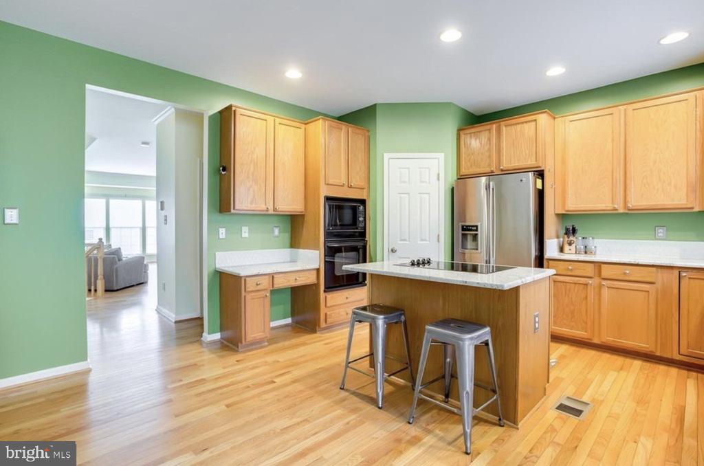 Kitchen with green walls, light wood cabinets, a central island and stainless steel appliances.
