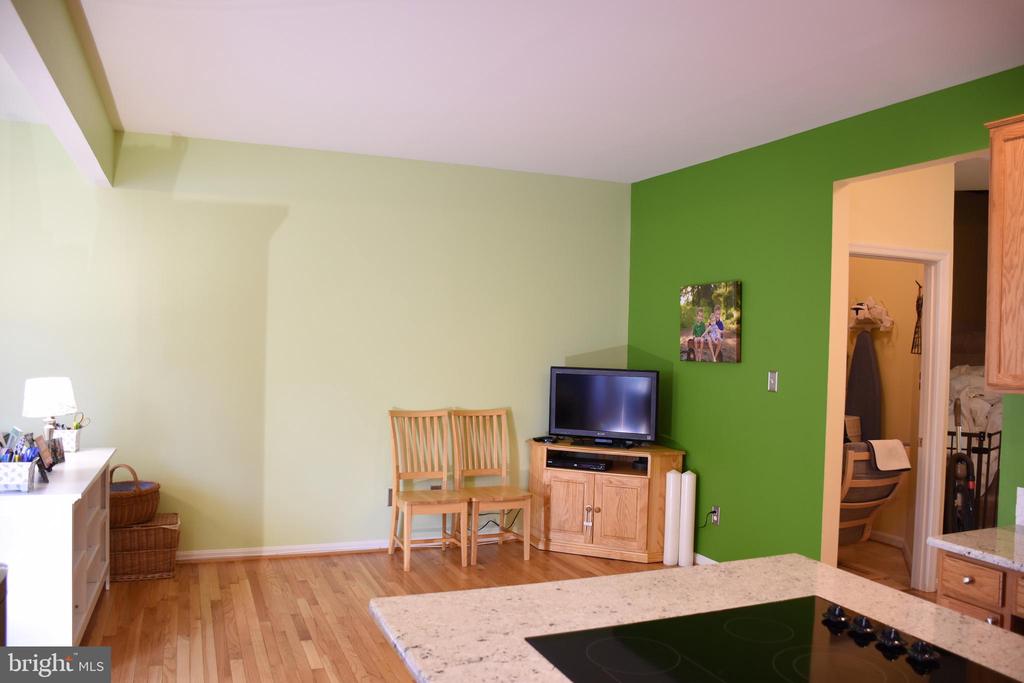 Kitchen with granite island and black cooktop, hardwood flooring, and a green accent wall.