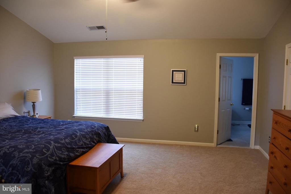 Bedroom with a blue patterned bedspread, wooden furniture, and a window with white blinds.
