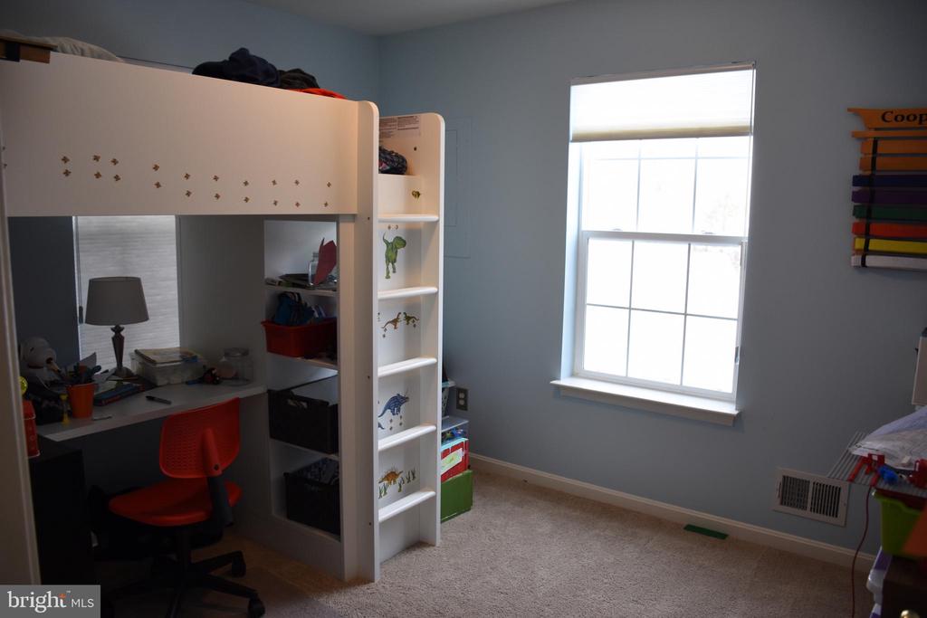 Child’s bedroom with a white loft bed and desk beside a large window.