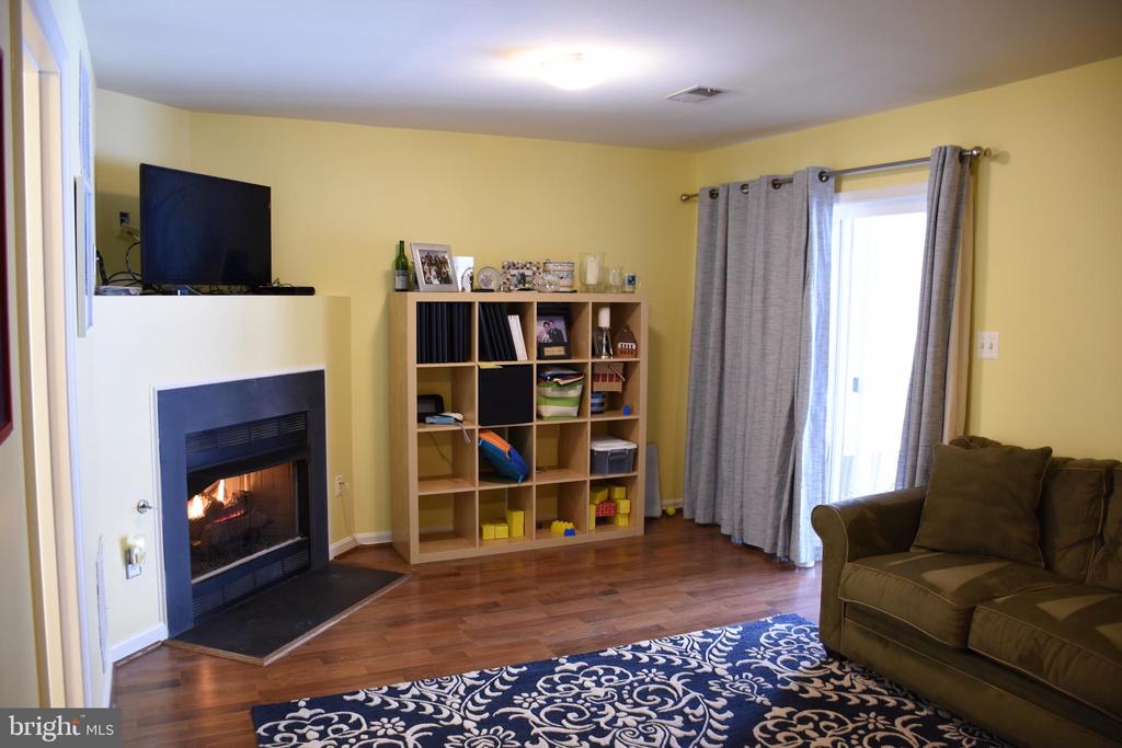 Living room with a lit fireplace, hardwood floors, a cubby bookcase, and a sliding glass door.