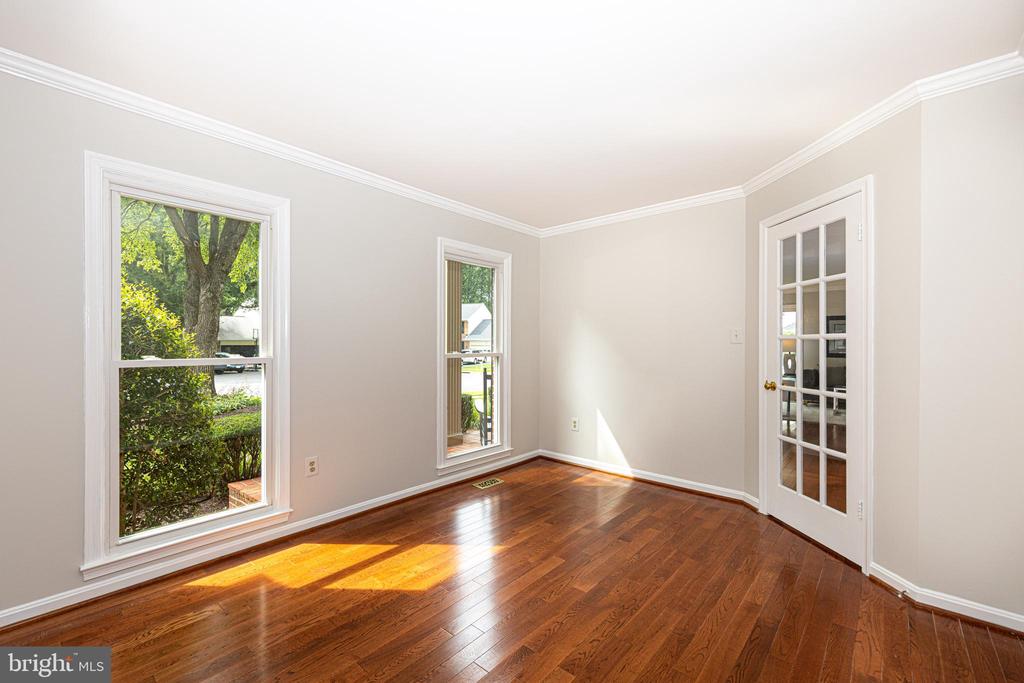 Vacant room with hardwood floors, two windows, and a glass-paneled French door.