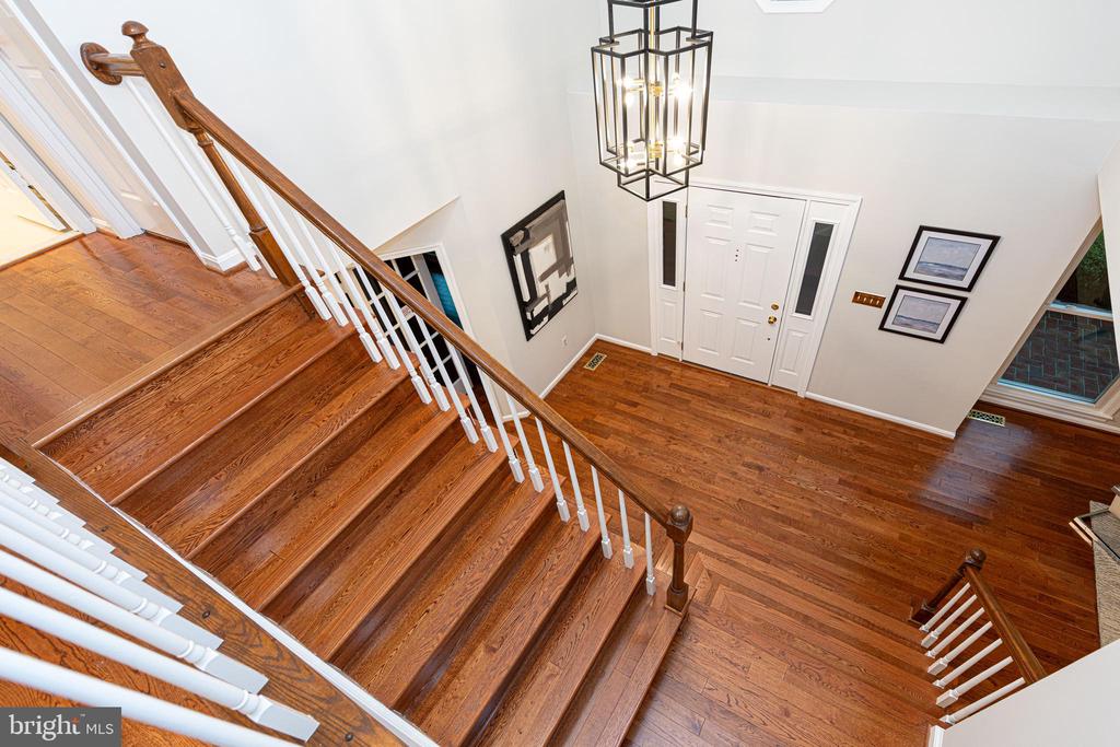 Two-story foyer with a broad hardwood staircase, white balusters, and a hanging lantern.