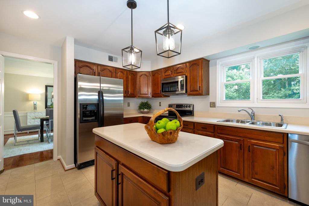Kitchen with wood cabinets, stainless steel appliances, and a central island topped with a basket of green apples.