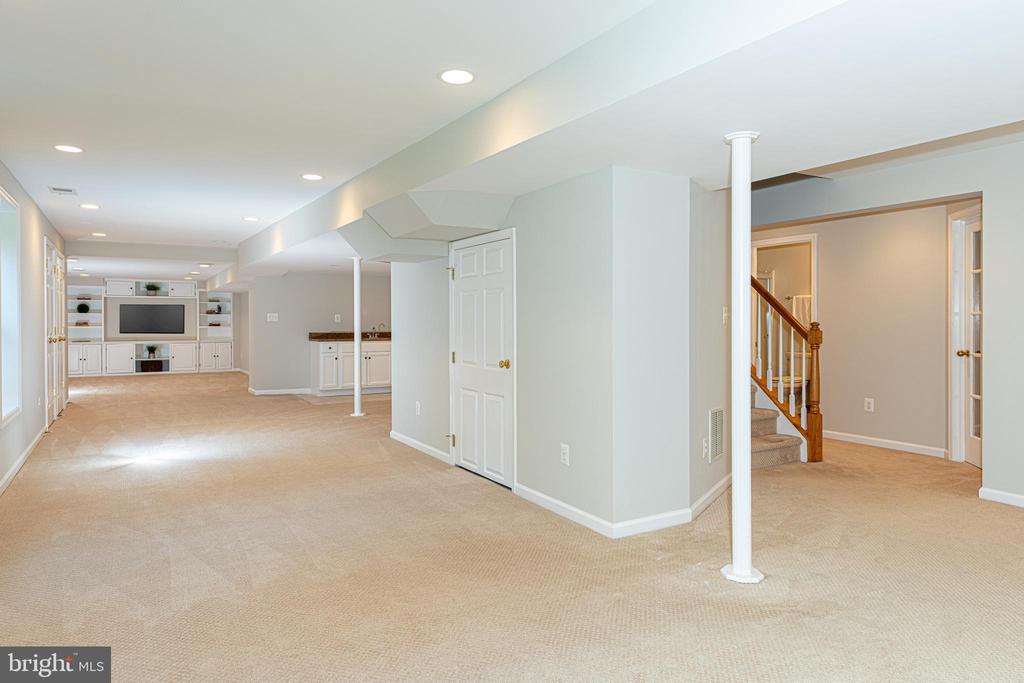 Finished basement with carpet, built-in media center, cabinets, and a staircase.