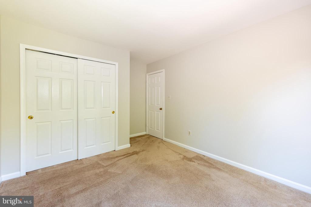 Empty carpeted room with white double closet doors and a separate entry door.