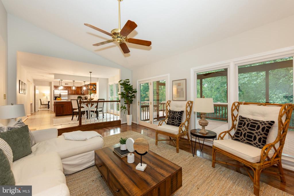 Living room with wicker armchairs, a wood coffee table, and large windows overlooking greenery.