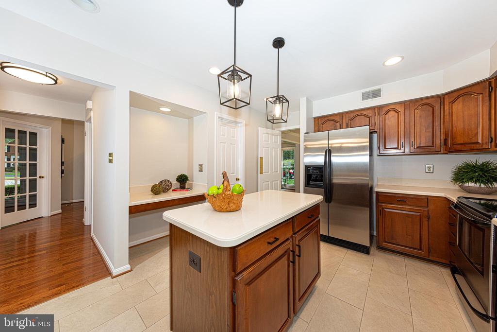 Kitchen with a white island, warm wood cabinets, and stainless steel appliances.