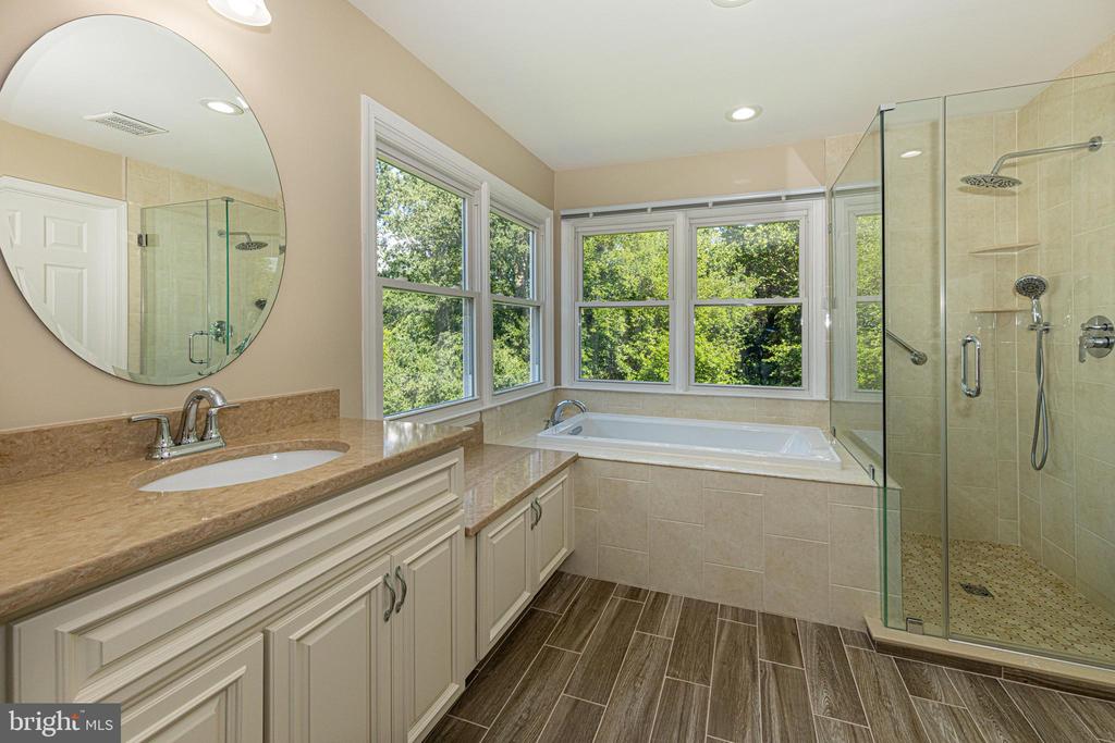 Bathroom with a soaking tub beneath wide windows and a glass-enclosed shower.