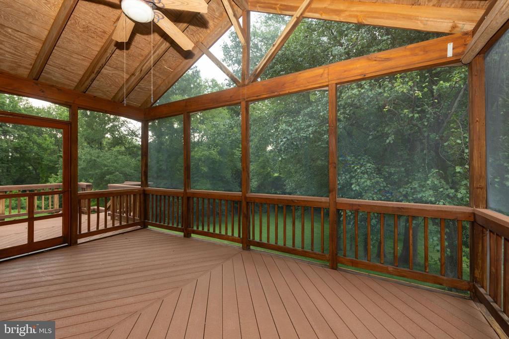 Screened porch with a peaked wood ceiling and wooded views through large screens.