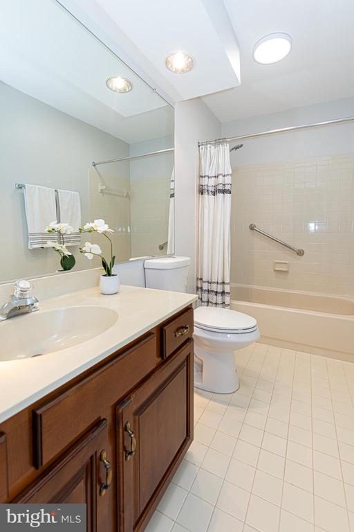 Bathroom with a dark wood vanity, white sink, toilet, and bathtub behind a striped shower curtain.